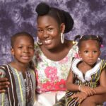 Happy African family of mother and children in traditional Ghanaian attire, radiating joy.